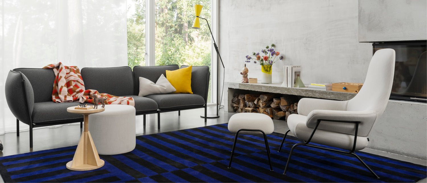 Hem - A living room scene featuring Kumo Sofa, Stripe Rug, All Wood Stool Rocket, Hai Lounge Chair + Ottoman, Storm Cushions, Vienna Throw, and an Alphabeta Floor Lamp.