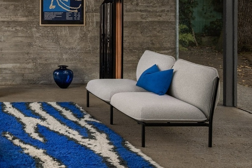 A living room scene featuring Kumo 2-Seater Sofa in Porcelain, Storm Cushion Large Sky, and Monster Rug Ultramarine Blue / Off-White.