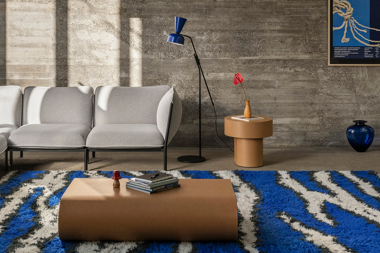 A living room scene featuring Kumo Sofa in Porcelain, Monster Rug Ultramarine Blue / Off-White, Stump Coffee Table Medium Natural, Alphabeta Floor Lamp Blue and Stump Side Table Natural.