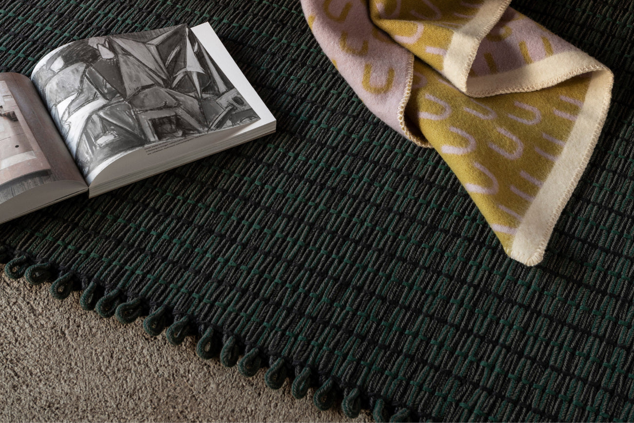 A close-up image of the Rope Rug in Pine with an Arch Throw in Pistachio / Lilac / Cream.