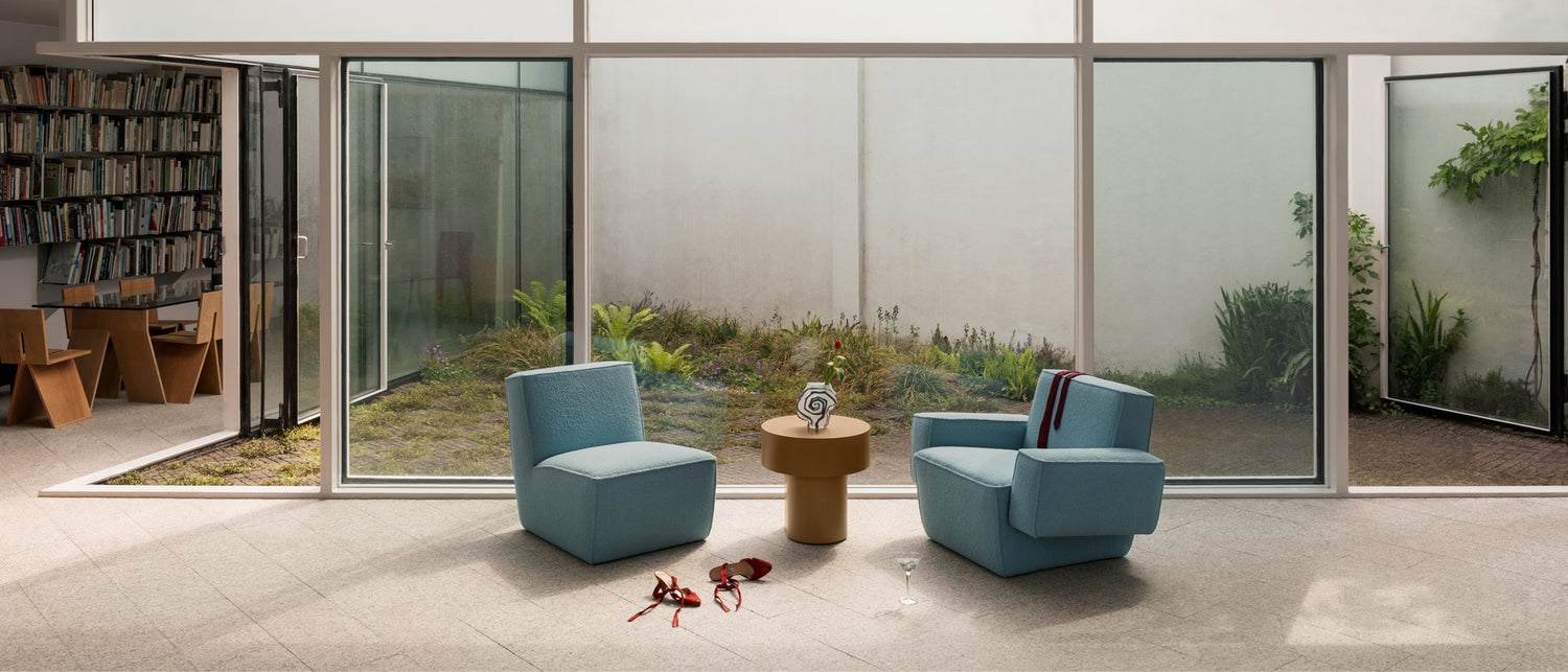 A lounge scene featuring Hunk Lounge Chair and Hunk Lounge Chair with Armrests in Icicle, with a Stump Side Table Natural in between the chairs.