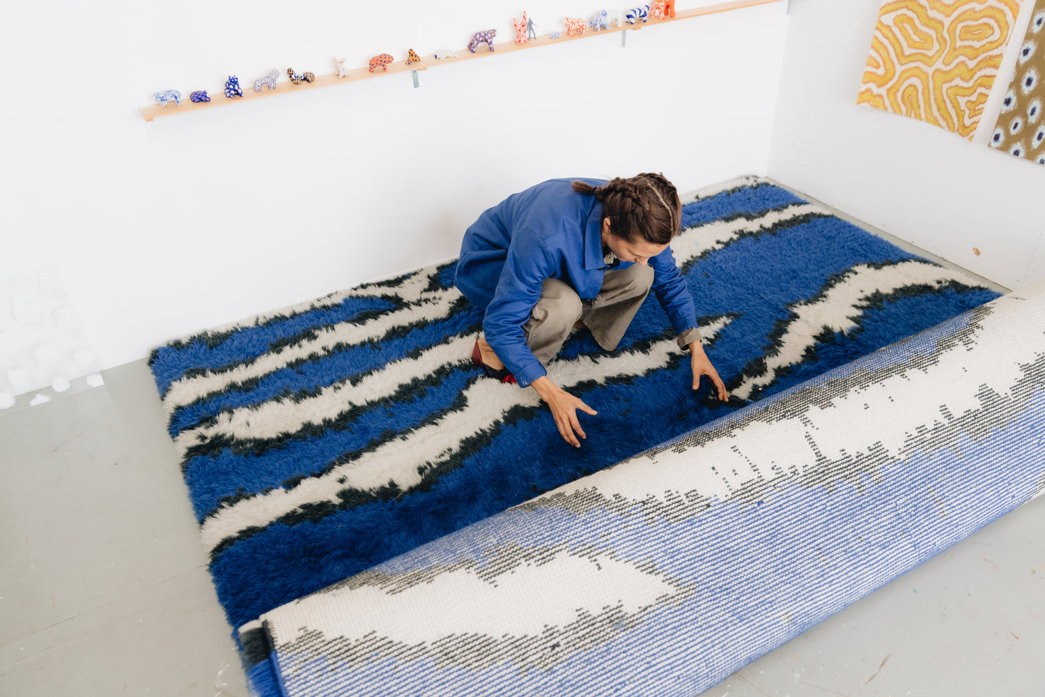 Designer Siri Carlén rolls out a Monster Rug in Ultramarine Blue / Off-White onto the floor.