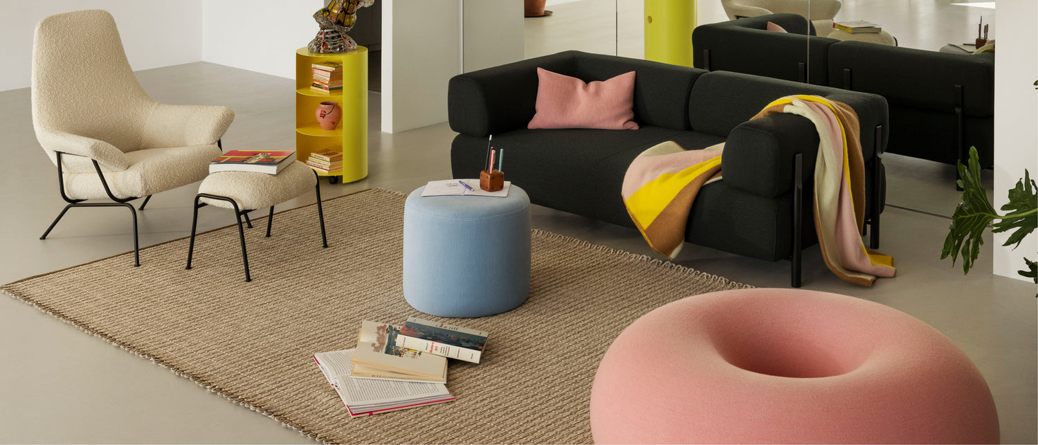 Hem - A colorful living room scene featuring Hai Lounge Chair + Ottoman, Rope Rug, Boa Pouf, Bon Pouf Round, Hide Pedestal, Palo 2 Seater Sofa + Armrests, Block Throw, and Neo Cushion Large.