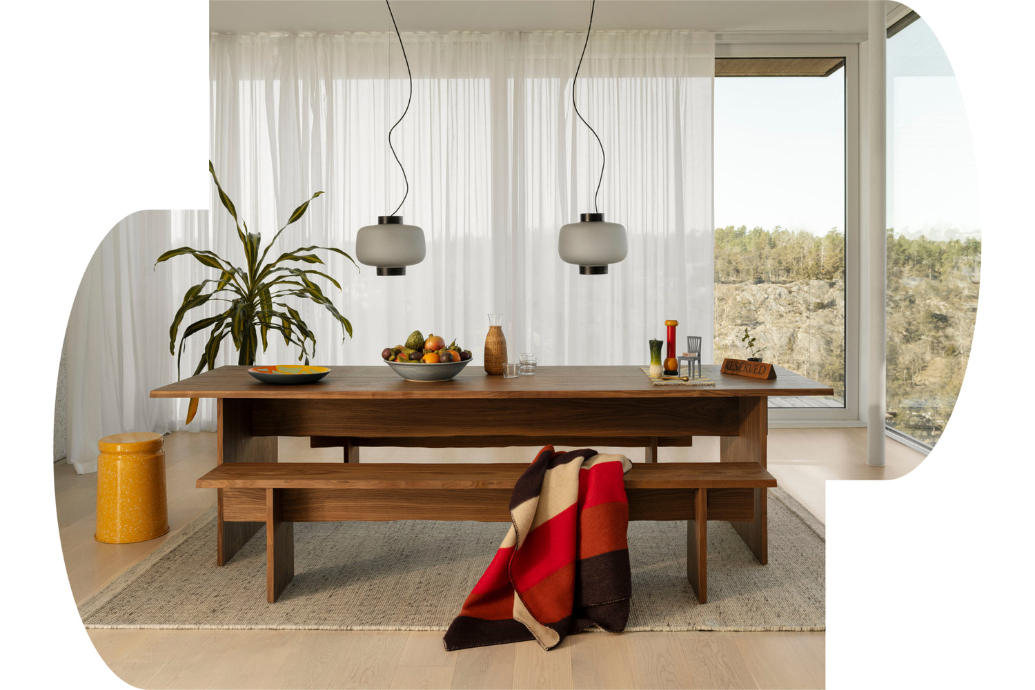 A Hem dining room scene featuring the Bookmatch Table + Bench Set in Walnut, Dusk Lamps, Dune Rug and Last Stool.